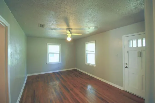 a view of an empty room with wooden floor and a window