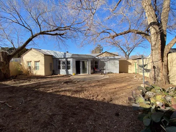 a backyard of a house with large trees and outdoor seating