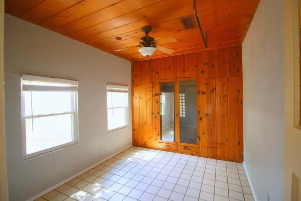 a view of an empty room with window and chandelier fan