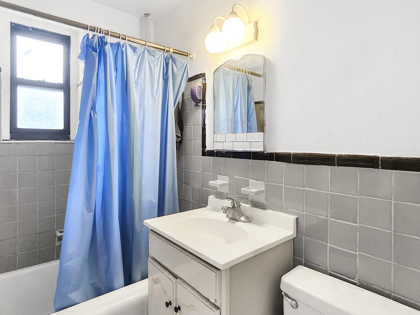 139-15 28th Road, Unit 1F Queens, NY 11354 - Photo 6 of 6 Full bathroom featuring shower / bath combination with curtain, vanity, toilet, and tile walls
