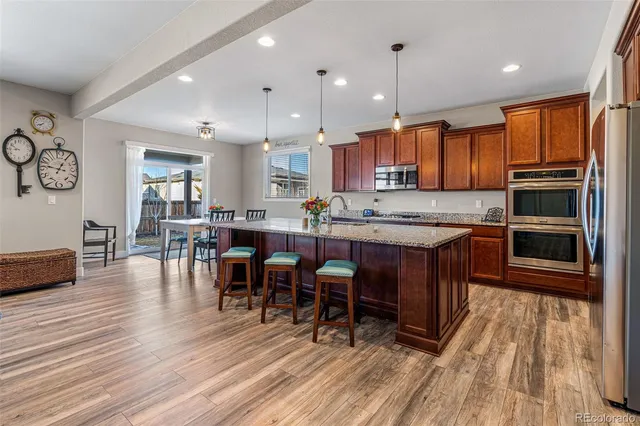 a kitchen with stainless steel appliances granite countertop a table chairs stove and refrigerator