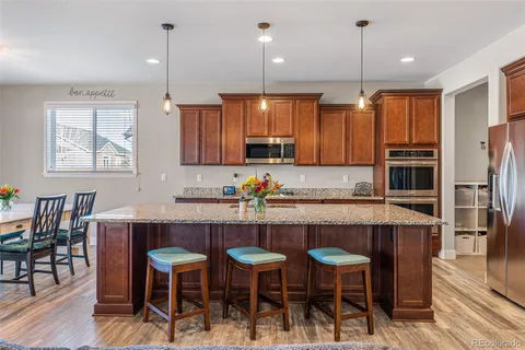 a kitchen with stainless steel appliances granite countertop a table chairs stove and refrigerator