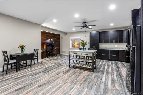 a kitchen with stainless steel appliances kitchen island granite countertop a stove top oven a sink a dining table and chairs with wooden floor