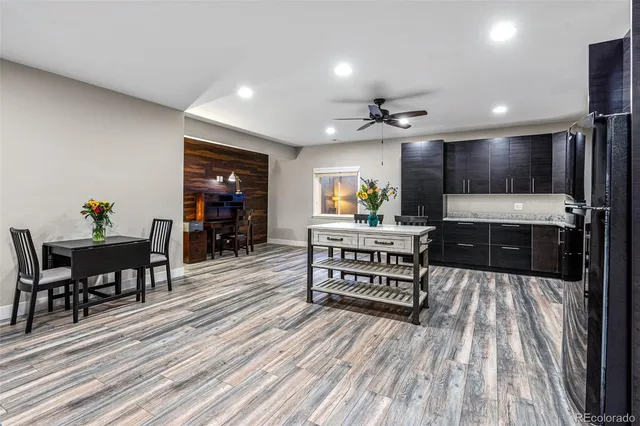 a kitchen with stainless steel appliances kitchen island granite countertop a stove top oven a sink a dining table and chairs with wooden floor