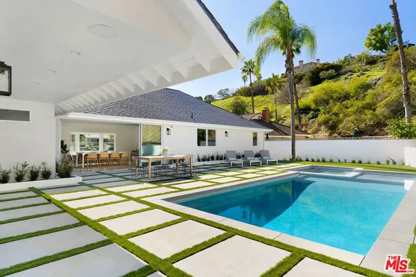a view of swimming pool with lawn chairs and plants