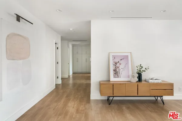 a view of a hallway with wooden floor and a bookshelf