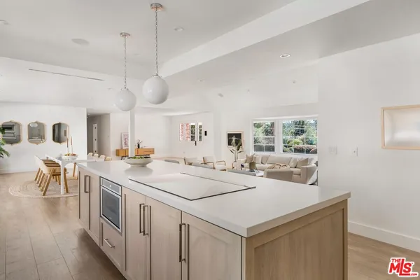 a kitchen with a stove a sink a center island and wooden floor