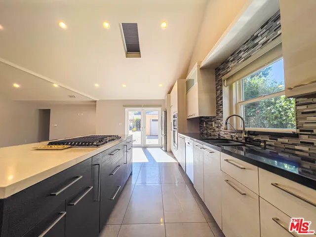 a large kitchen with stainless steel appliances granite countertop a stove a sink and a refrigerator