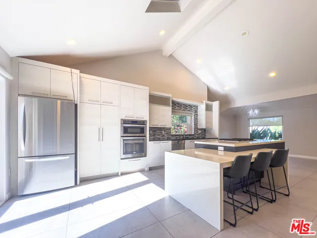 a kitchen with a sink a refrigerator and chairs
