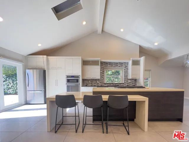 a dining hall with stainless steel appliances a dining table and chairs