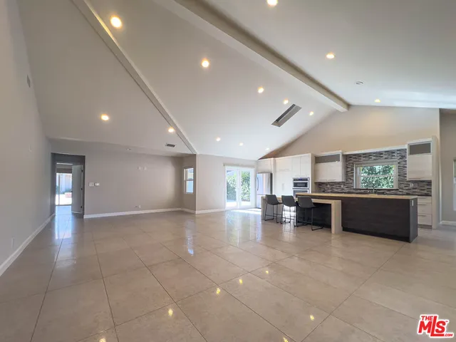 a view of empty room with kitchen and window