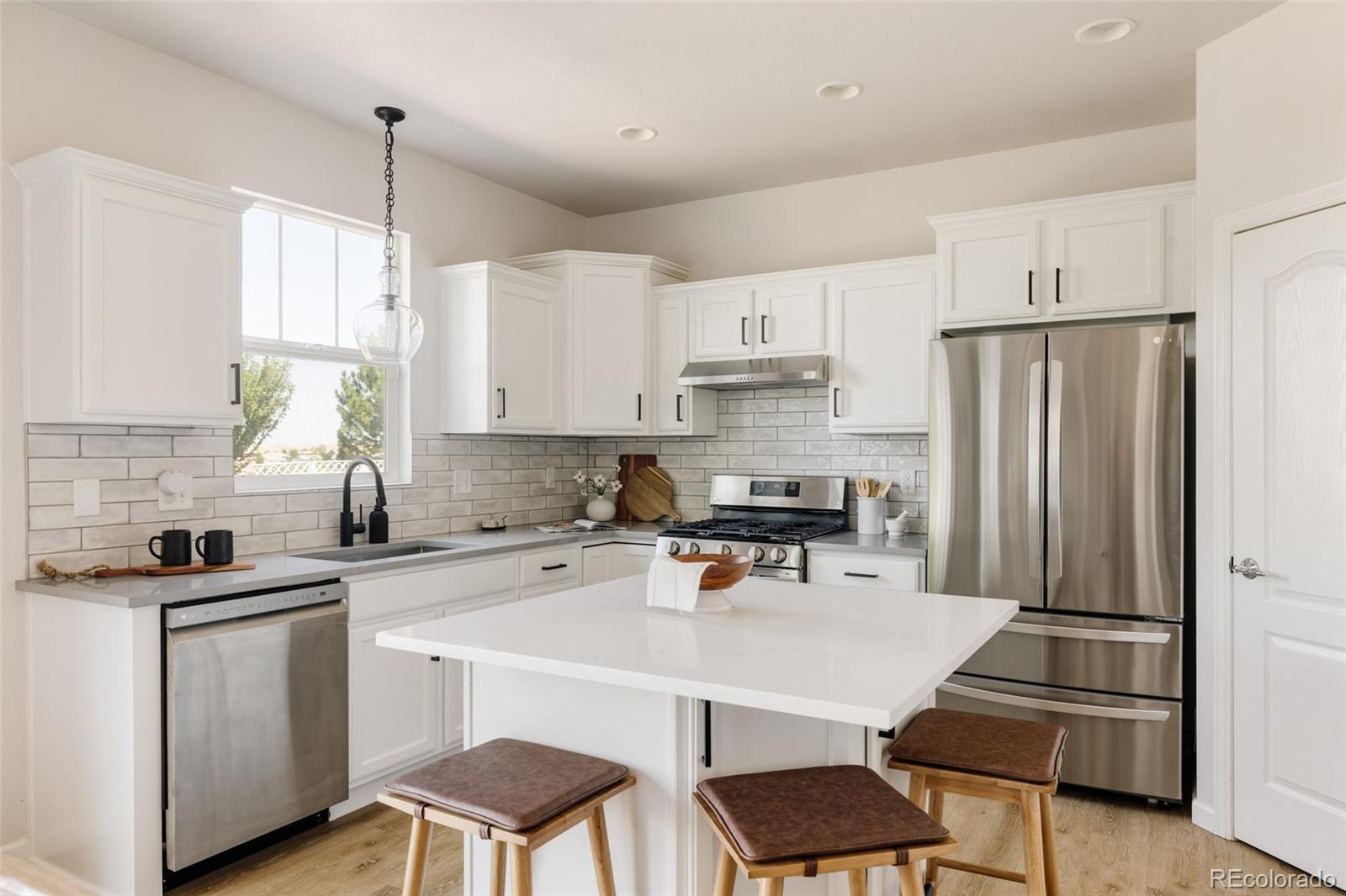 2899 Trinity Loop Broomfield, CO 80023 - Photo 7 of 33 a kitchen with stainless steel appliances a table chairs refrigerator and microwave