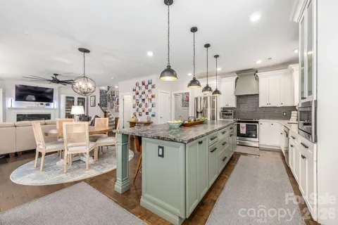 a view of a dining room and livingroom with furniture wooden floor a chandelier