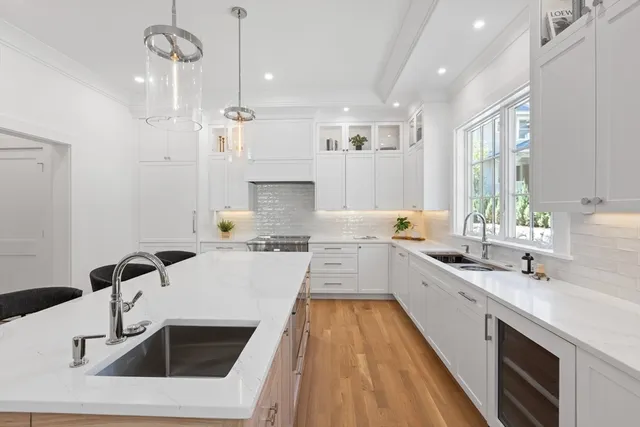 a large white kitchen with a sink a counter top space stainless steel appliances and a window
