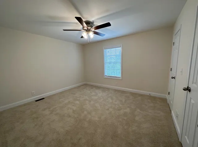 an empty room with windows and fan