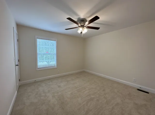 an empty room with windows and fan