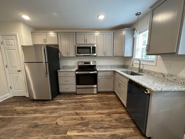 a kitchen with granite countertop a refrigerator a sink a stove a microwave and island