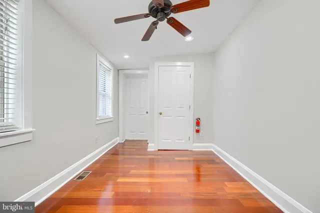 a view of empty room with wooden floor and fan