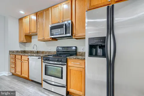 a kitchen with stainless steel appliances granite countertop a sink and a refrigerator