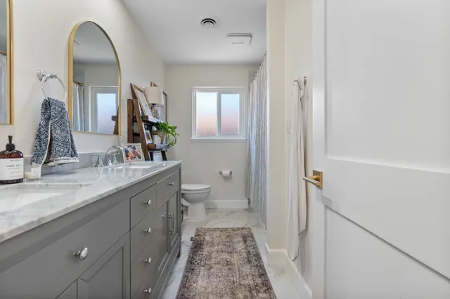 a bathroom with a granite countertop sink a large mirror and a toilet