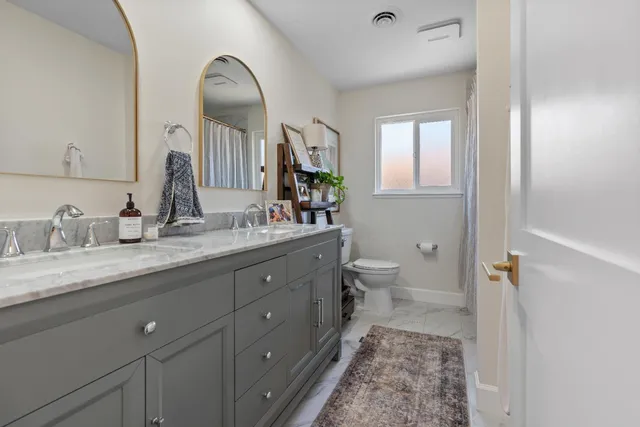 a spacious bathroom with a granite countertop sink a toilet and a mirror
