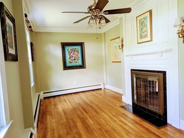 a view of an empty room with wooden floor and a fireplace