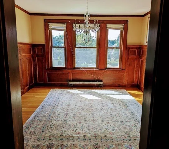 a view of a hallway with wooden floor and a chandelier