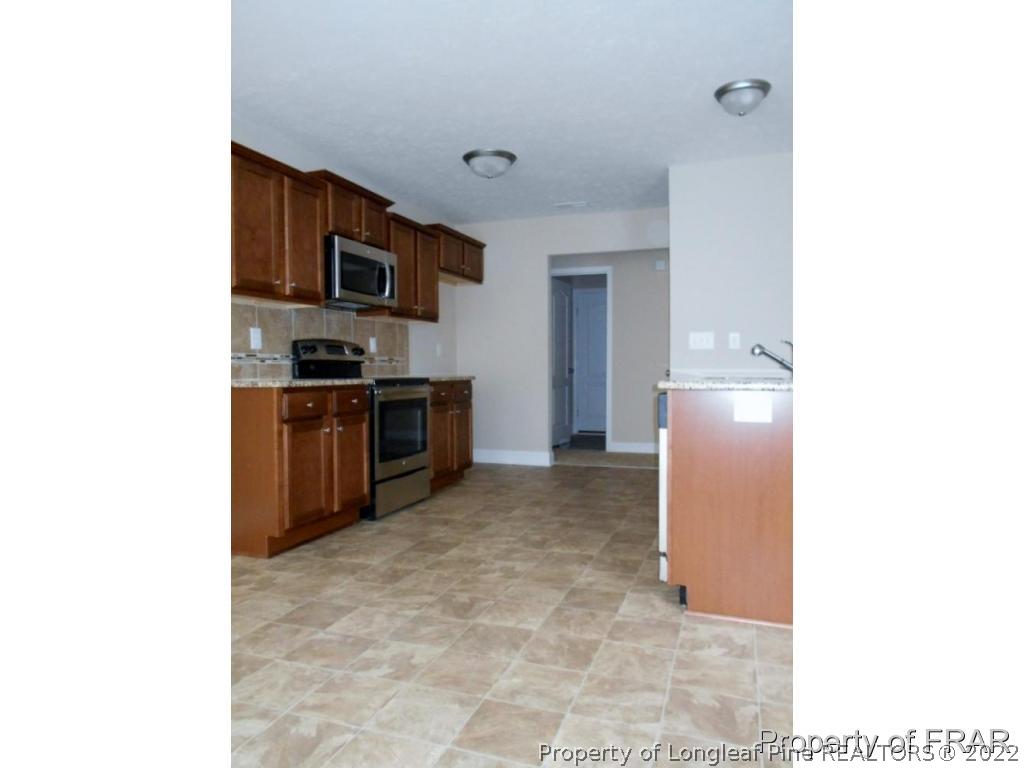 3126 Thrower Road Hope Mills, NC 28348 - Photo 6 of 22 a kitchen with stainless steel appliances granite countertop a refrigerator and a stove