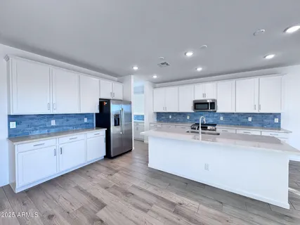 a large kitchen with stainless steel appliances granite countertop a stove a sink a refrigerator and white cabinets