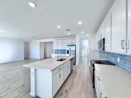 a large kitchen with a large counter top a sink stainless steel appliances and cabinets