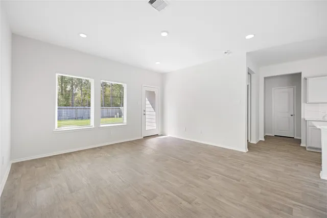 an empty room with wooden floor and windows