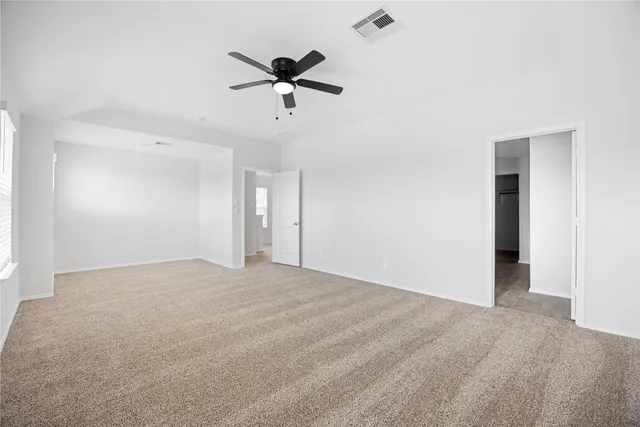 a view of an empty room and chandelier fan