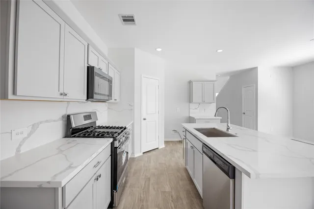 a kitchen with stainless steel appliances granite countertop a sink stove and cabinets