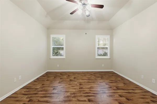 an empty room with wooden floor and windows