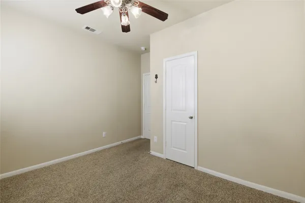 an empty room with a chandelier fan and closet