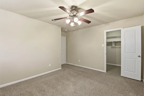an empty room with closet and a chandelier fan