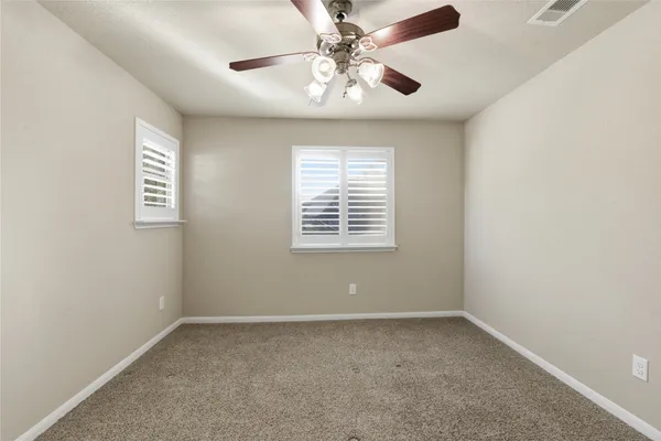 an empty room with a window and a fan