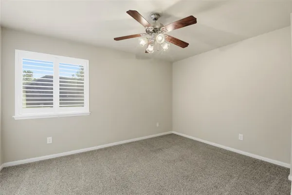 an empty room with a chandelier fan and windows