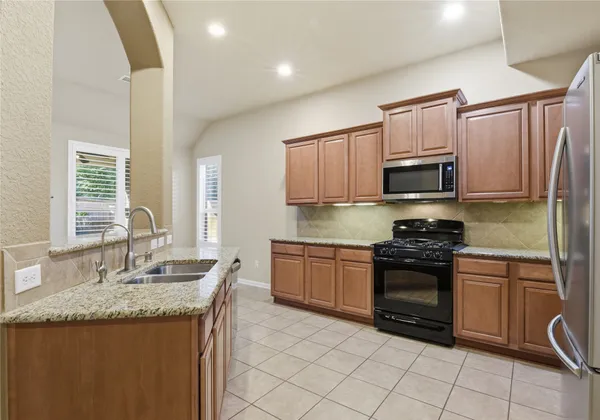 a kitchen with kitchen island granite countertop a stove sink and microwave