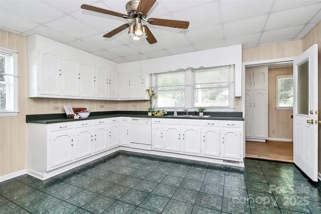 a kitchen with granite countertop white cabinets white stainless steel appliances with a sink and a window