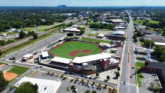 an aerial view of a tennis ground and a cars park side of the road