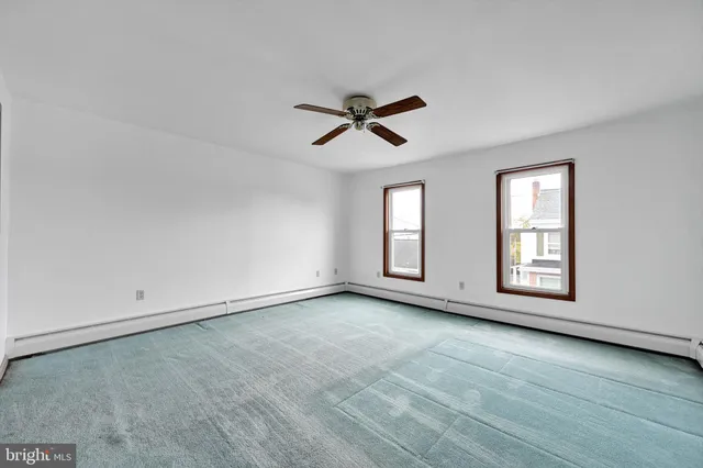 an empty room with chandelier fan and windows