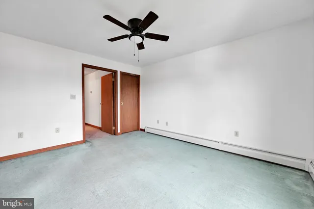an empty room with chandelier fan and windows