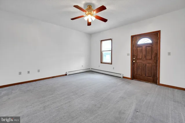 an empty room with chandelier fan and windows