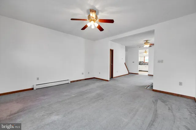 an empty room with ceiling fan and window