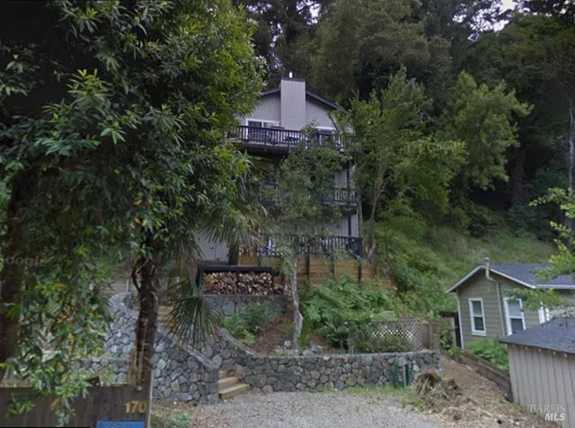 a front view of a house with a yard and large tree
