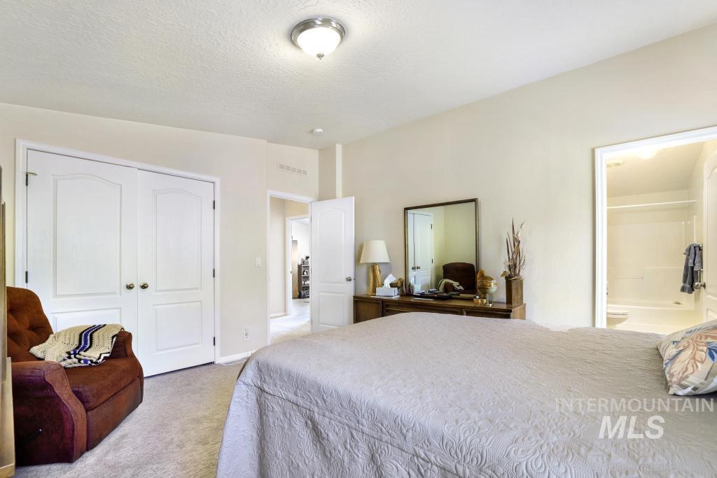 910 Moonglo Road, Unit 14 Buhl, ID 83316 - Photo 13 of 22 Bedroom featuring light colored carpet, ensuite bathroom, a closet, and a textured ceiling
