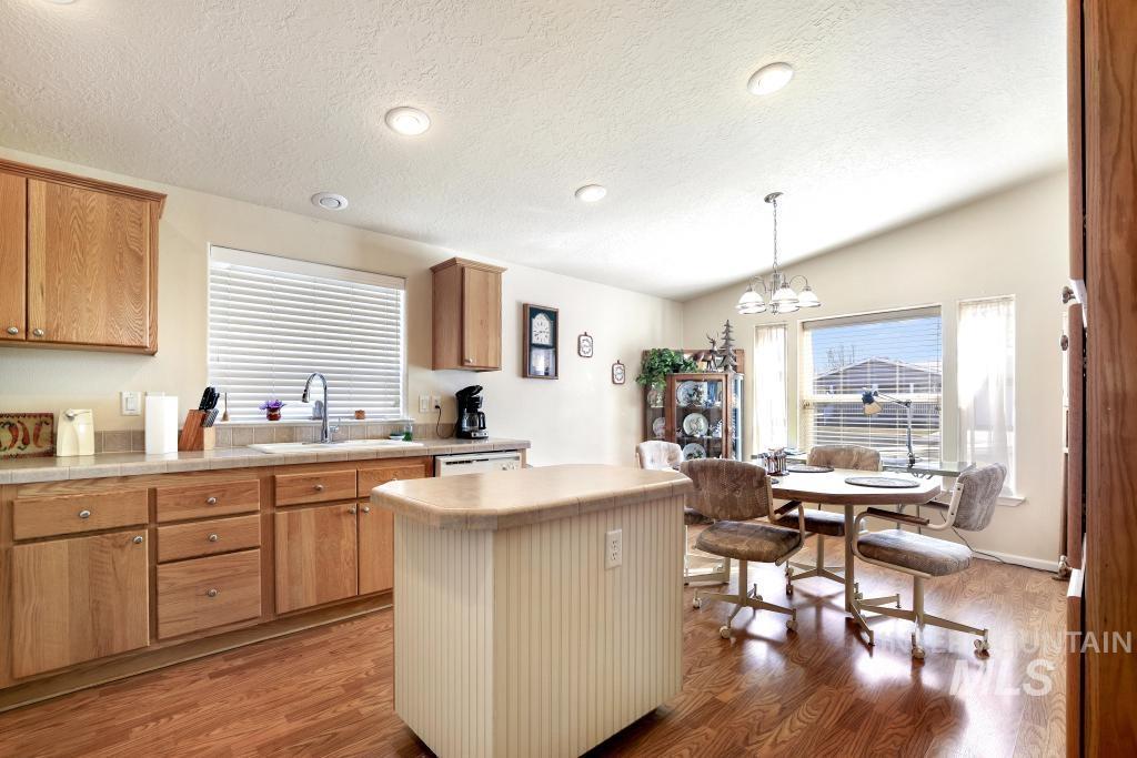 910 Moonglo Road, Unit 14 Buhl, ID 83316 - Photo 7 of 22 Kitchen with light countertops, a kitchen island, dark wood-style floors, hanging lights, and a textured ceiling
