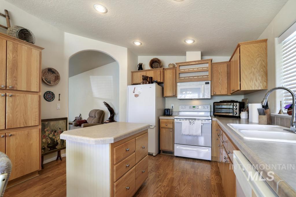 910 Moonglo Road, Unit 14 Buhl, ID 83316 - Photo 9 of 22 Kitchen featuring white appliances, a kitchen island, dark wood finished floors, light countertops, and wood finish cabinets