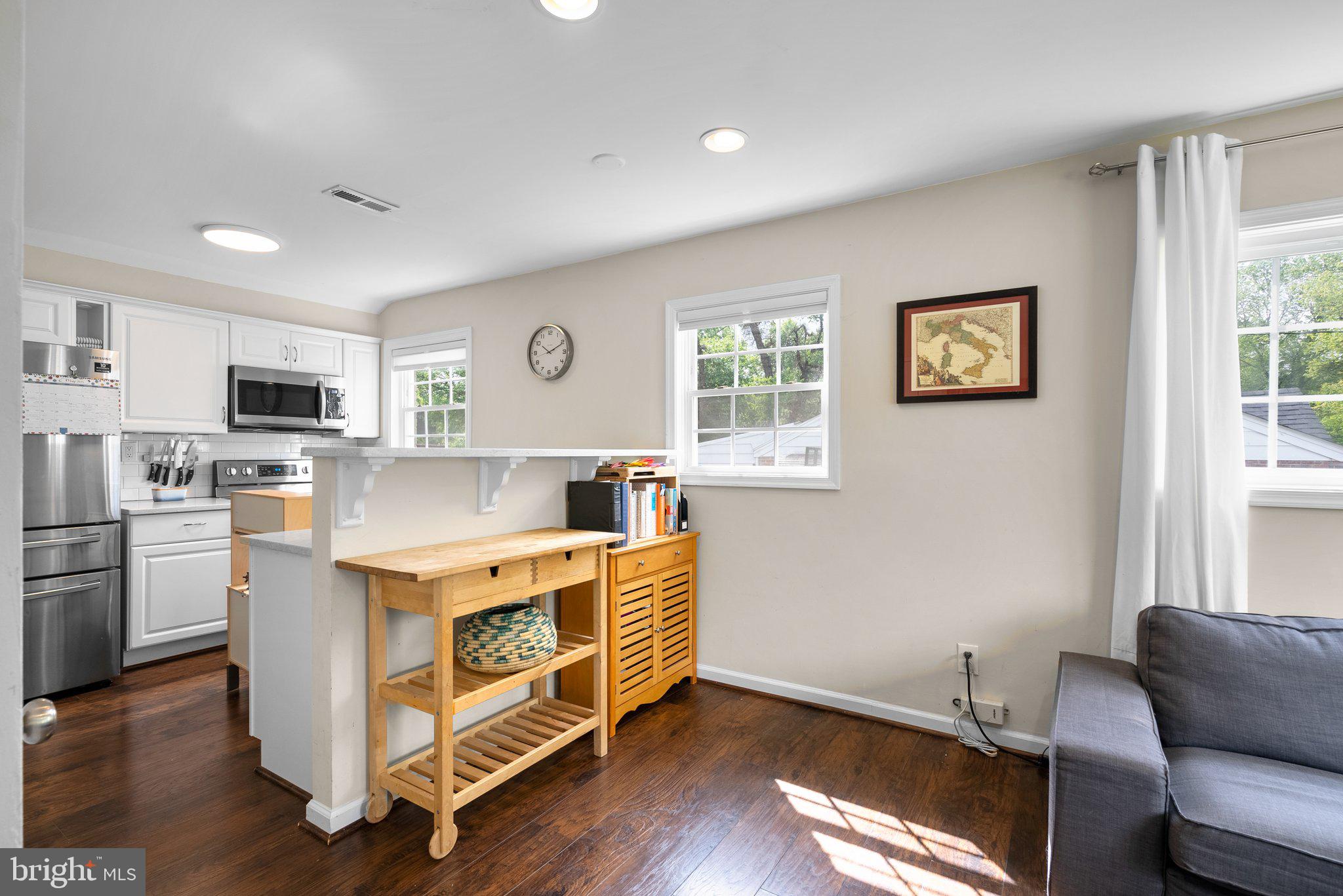 12837 Flack Street Silver Spring, MD 20906 - Photo 7 of 26 a view of kitchen with stainless steel appliances granite countertop a stove top oven a refrigerator a kitchen island and couches with wooden floor